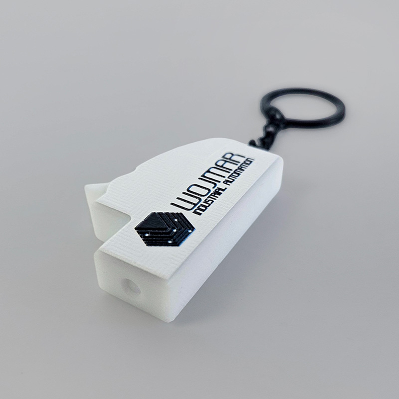 3D keychains made of hard resin, black and white, shaped like a circuit breaker, with raised logo and inscriptions, Polish manufacturer DECARD.