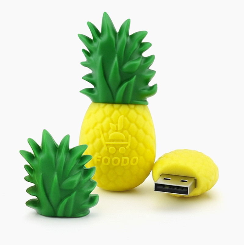 A 3D USB pendrive shaped like a pineapple with a juicy fruit texture. The cap is designed as the leaves, and the FOODO logo appears in 3D on the edges, with realistic colors. Designed by the Polish manufacturer DECARD