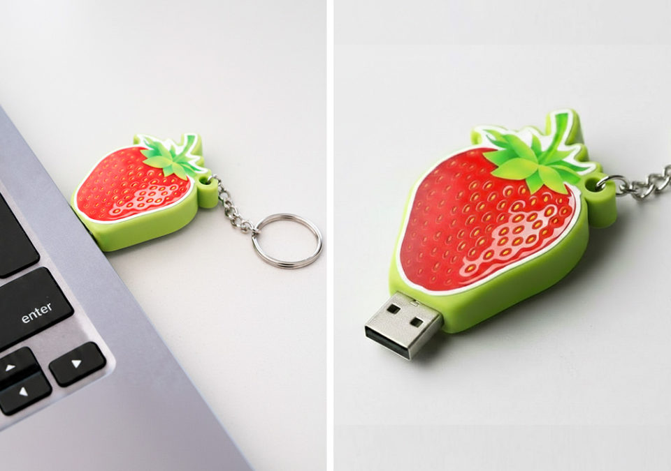 D strawberry-shaped USB flash drive, capless, close-up showing glossy embossed texture, inserted into a laptop, made by Polish manufacturer DECARD