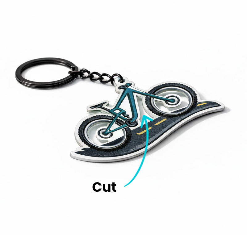 Bicycle-shaped keychain riding on a road, with a cutout between the road and the frame, made of hard resin, hanging on a backpack, made by the Polish manufacturer DECARD