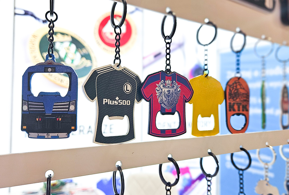 Keychains with bottle opener function – metal, sports jerseys with crests, train – hanging at the DECARD booth during PROMO SHOW 2026
