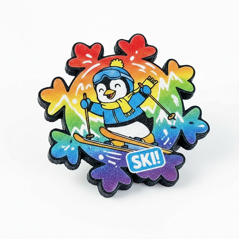 A colorful 3D snowflake-shaped pin with a penguin on skis, made from durable resin, perfect for winter events and promotions. Manufactured in Poland by DECARD