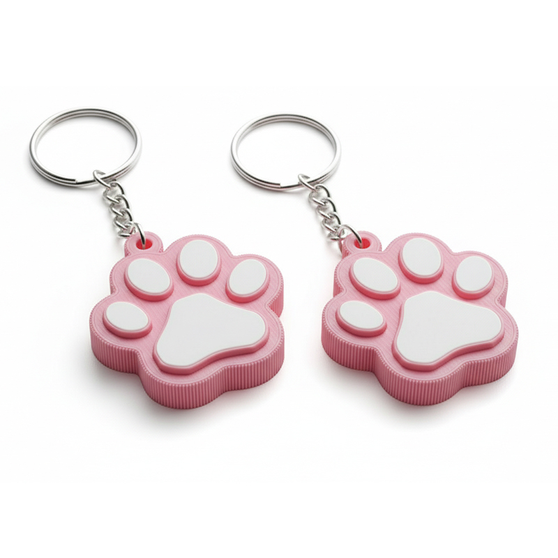 A 3D keychain in the shape of an animal paw, made of hard resin, with vivid pastel colors and a dedicated backing card, featuring decorative 3D patterns along the edges. Manufactured in Poland by DECARD