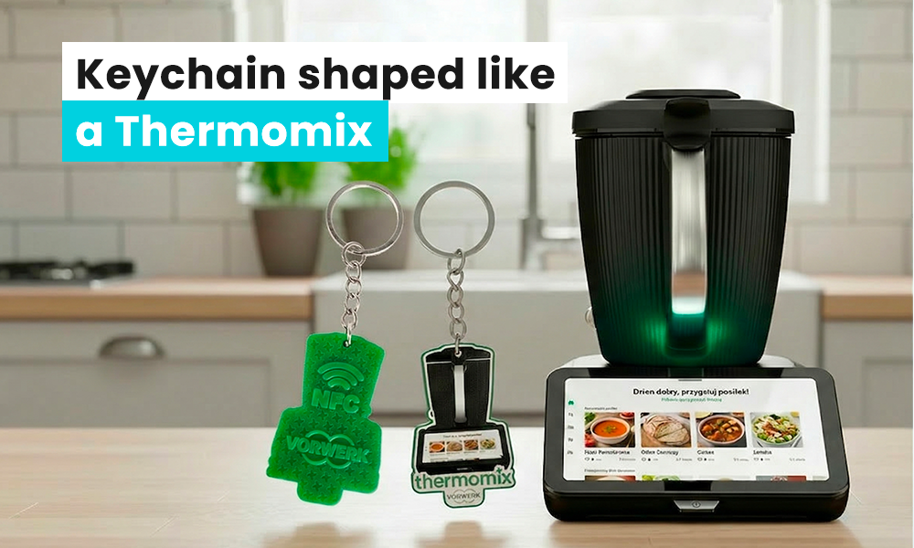 NFC keychain shaped like a Thermomix placed next to a real Thermomix, with a kitchen in the background, produced by the Polish manufacturer DECARD