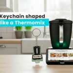 An NFC keychain shaped like a Thermomix placed next to a real Thermomix, with a kitchen in the background, made by the Polish manufacturer DECARD