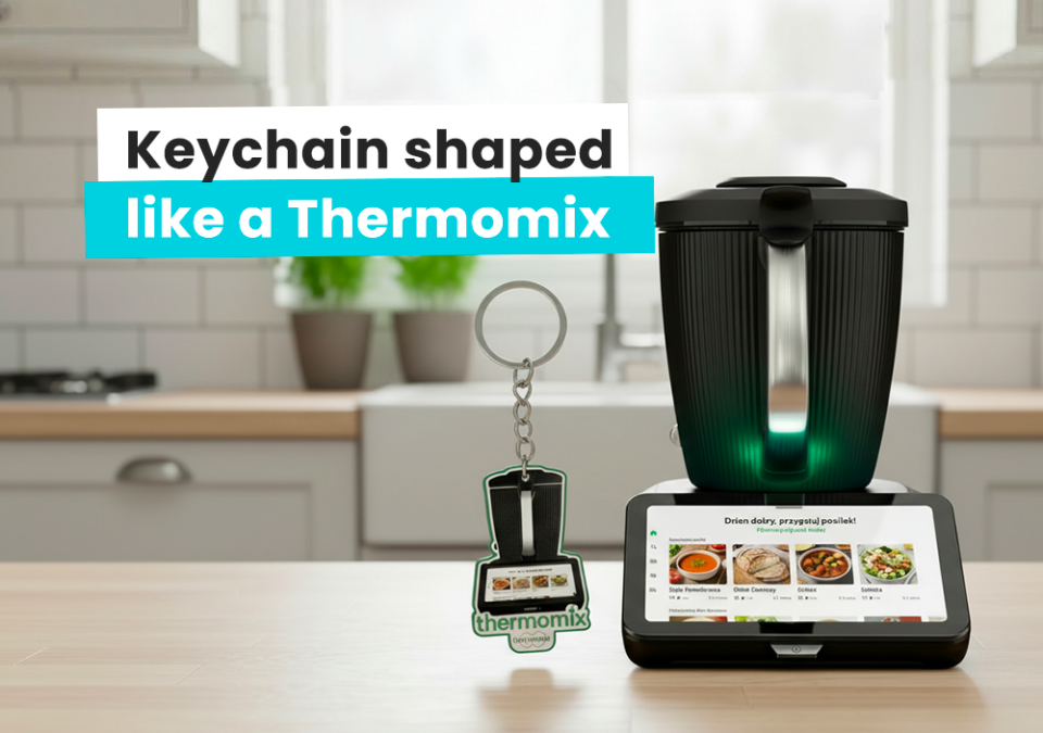 An NFC keychain shaped like a Thermomix placed next to a real Thermomix, with a kitchen in the background, made by the Polish manufacturer DECARD
