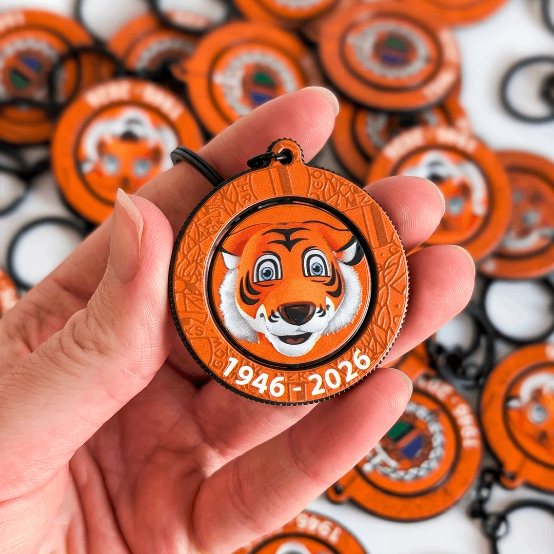 Rotating tiger keychain held in a hand, with scattered tiger keychains in the background. Manufactured by Polish promotional merchandise producer DECARD
