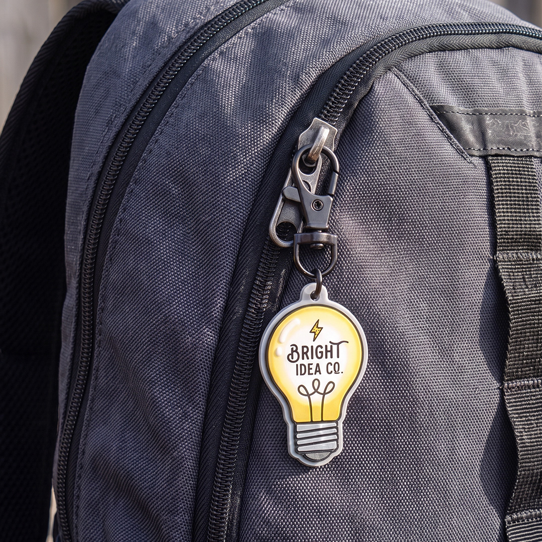 Light bulb keychain with a carabiner attached to a grey backpack