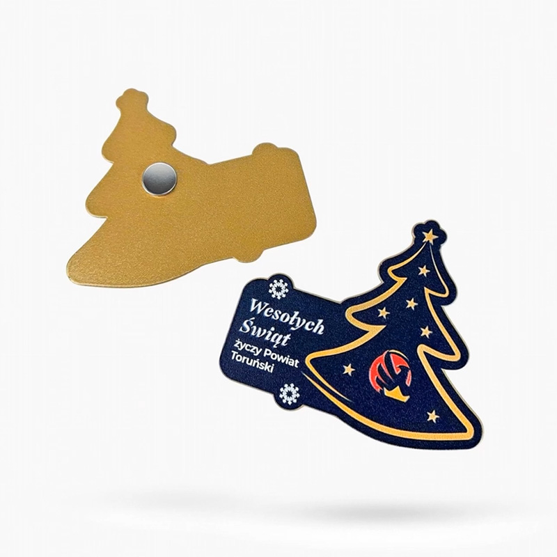 Magnes metalowy choinka dla powiatu toruńskiego, wypukłe elementy graficzne: logo, życzenia, gwiazdki, z tyłu złoty kolor, polski producent DECARD