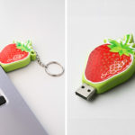 Pendrive przestrzenny w kształcie truskawki, bez zatyczki, zbliżenie na wypukłą teksturą w połysku, i włożony do laptopa, wykonanie polski producent DECARD