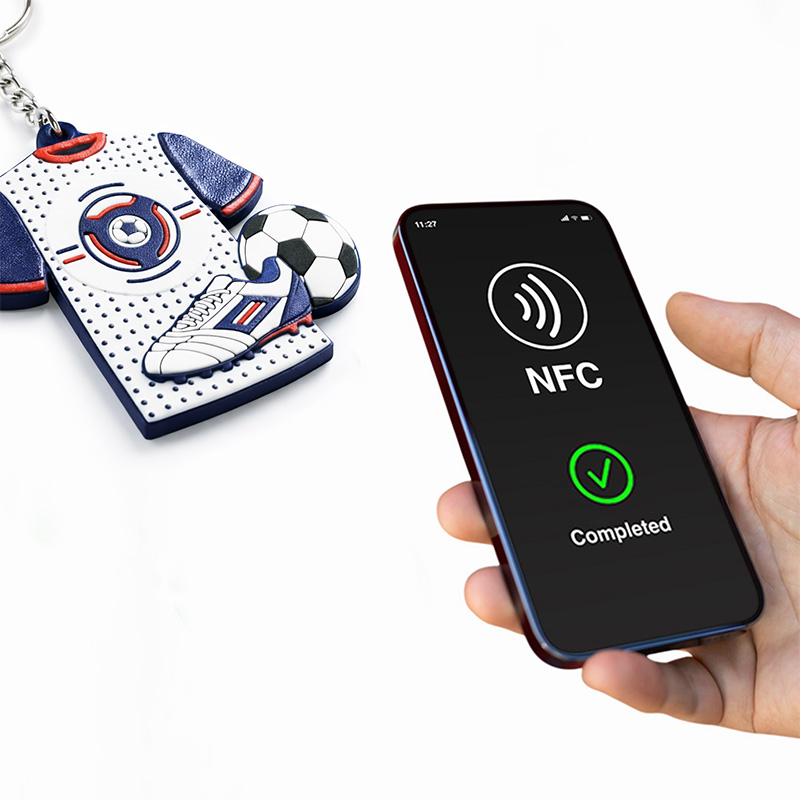 Brelok w kształcie koszulki sportowej, telefon w ręku skanujący kod NFC