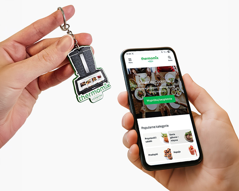 Brelok NFC w kształcie Thermomixa przyłożony do telefonu, z przekierowaniem na stronę Thermomix Polska, wykonanie breloka polski producent DECARD