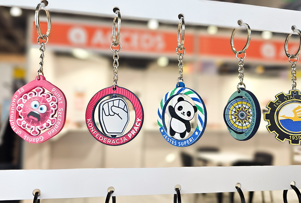 Breloki obrotowe wirus, dłoń, panda, wiszące na stoisku DECARD podczas PROMO SHOW 2026