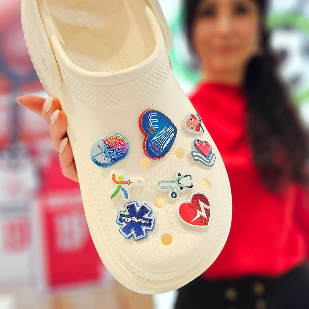 Medyczne przypinki na białych Crocsach w tle trzymająca w ręku buty Monika Witt z firmy DECARD